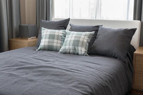 Дизайн інтер'єру спальні з перевіреними зеленими подушками на сірому ліжку та декоративна настільна лампа . — стокове фото
