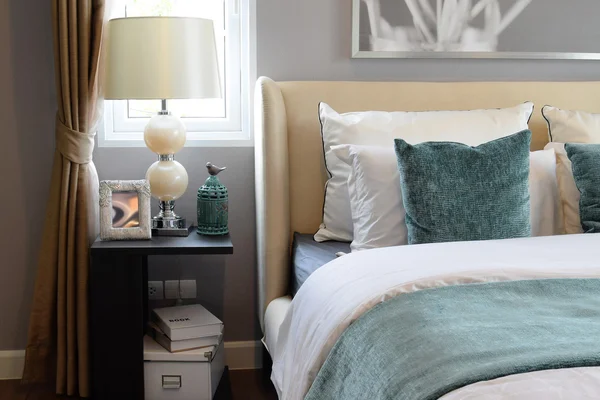 Dormitorio de diseño interior con almohadas blancas y verdes en la cama blanca y lámpara de mesa decorativa . — Foto de Stock