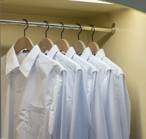 Rad med vita skjortor hängde på klädhängare i garderoben — Stockfoto