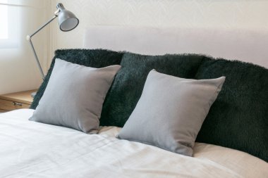 beyaz yatak ve dekoratif masa lambası gri yastık ile yatak odası iç tasarım.