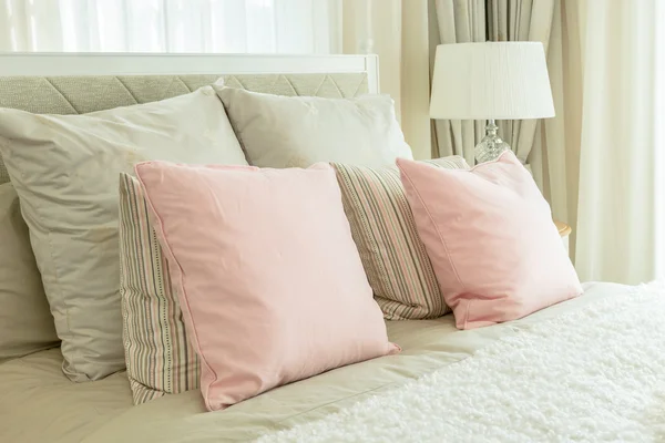 Aconchegante interior do quarto com travesseiros rosa e lâmpada de leitura na mesa de cabeceira — Fotografia de Stock