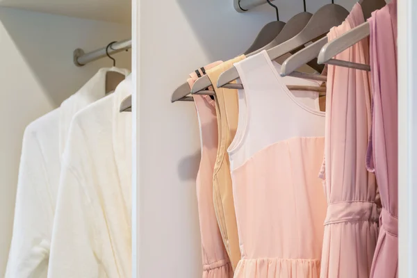 Fila de colorido vestido colgando en percha de abrigo en armario blanco — Foto de Stock