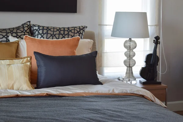 Moderno dormitorio interior con almohadas de color naranja y oro en la cama y lámpara de mesita de noche —  Fotos de Stock
