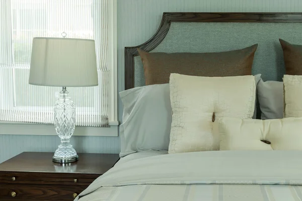 Cozy bedroom interior with white pillows and reading lamp on bedside table Royalty Free Stock Images