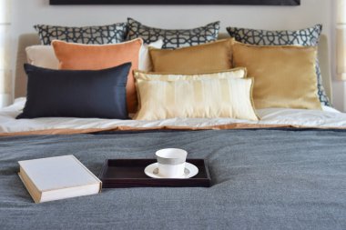 çay fincanı dekoratif ahşap tepsi ve beyaz kitabın yatağa sahip modern yatak odası iç