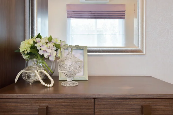 Tarro de cristal de joyería con marco de imagen y flores en la mesa de madera — Foto de Stock