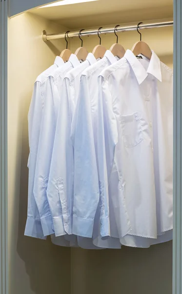 Linha de camisas brancas penduradas no cabide do casaco no guarda-roupa — Fotografia de Stock