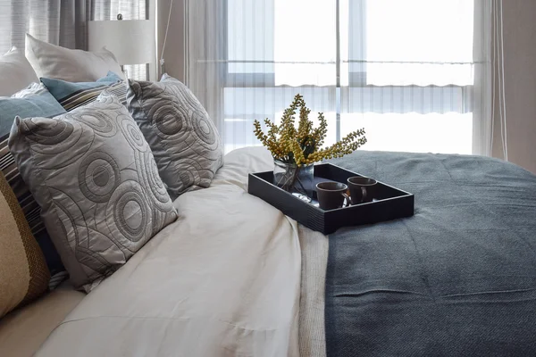 Diseño interior de dormitorio de lujo con almohadas a rayas y set de té decorativo en la cama — Foto de Stock