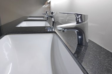 Beyaz lavabo ve musluk tuvalet granit sayaçta