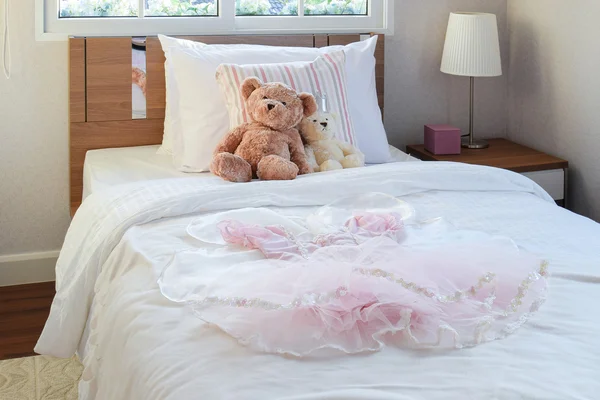 Bílá ložnice dekorační s holkou šaty, polštáře a panenky na posteli — Stock fotografie