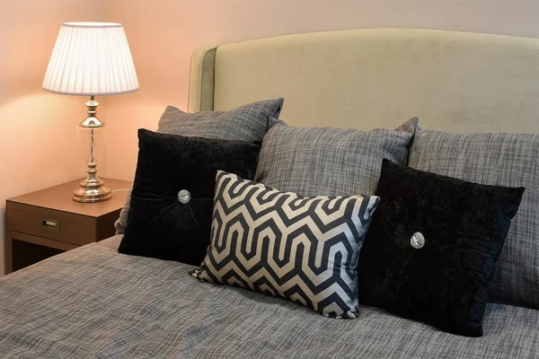 Stylové ložnice design interiéru s černé vzorované polštáře na posteli a dekorativní stolní lampa. — Stock fotografie