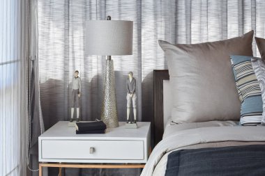 çizgili yastık yatak ve dekoratif masa lambası ile şık yatak odası iç tasarım.