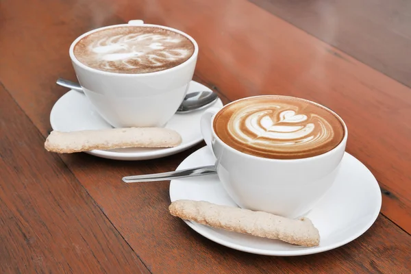 Deux tasses de café latte art dans une tasse blanche sur fond en bois — Photo