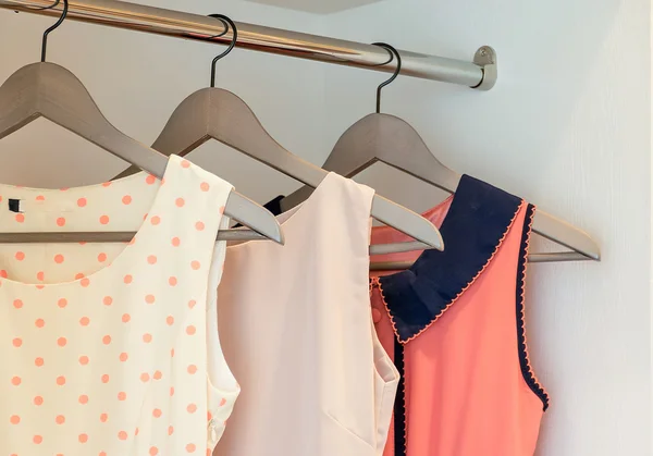 Fila di abito colorato appeso al appendiabiti in armadio bianco — Foto Stock