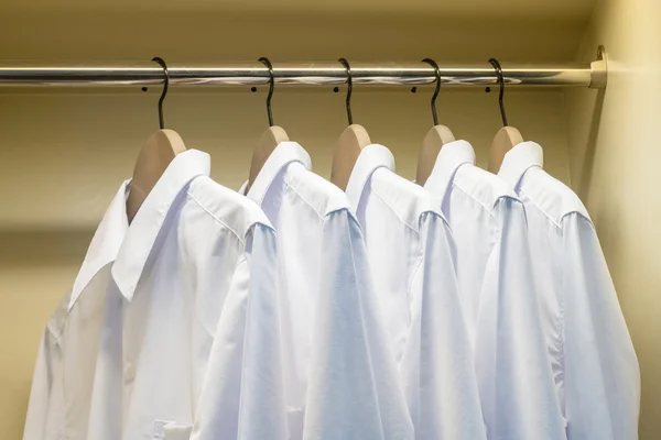 Närbild på vita skjortor hängde på klädhängare i garderoben — Stockfoto