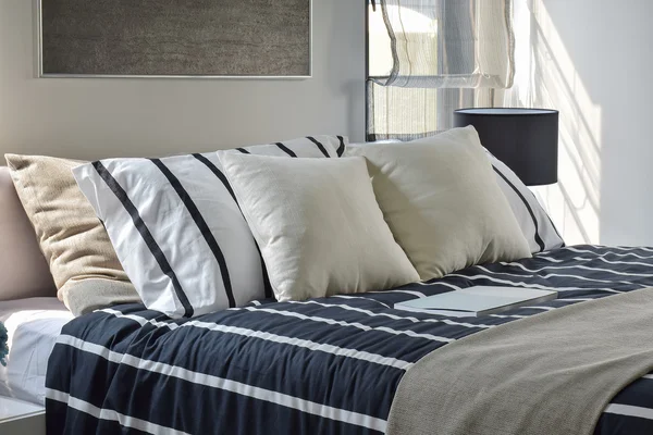 Offwhite and striped pillows on bed with deep blue striped blanket in modern style bedroom — Stock Photo, Image