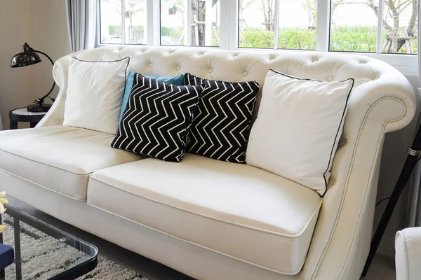 Λευκό και μπλε μαξιλάρια σε έναν λευκό δερμάτινο καναπέ σε εκλεκτής ποιότητας σαλόνι — Φωτογραφία Αρχείου