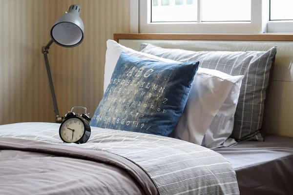 Svart väckarklocka i mysiga sovrum inredning med kuddar och läslampa — Stockfoto