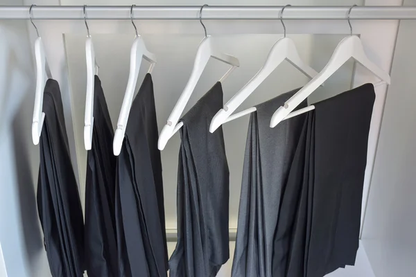 Šedé a černé kalhoty visí ve skříni doma — Stock fotografie
