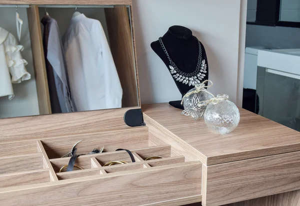 Crystal jars and necklace on wooden dressing table