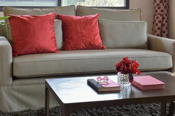 Sofá confortável com almofadas vermelhas e livro vermelho na mesa de madeira na área de estar — Fotografia de Stock