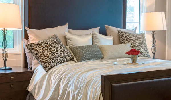 Interior del dormitorio de lujo con almohadas de patrón marrón y bandeja decorativa de flores en la cama — Foto de Stock
