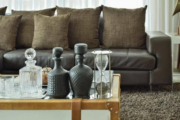 Set de bebidas de cristal y cristal de lija en la mesa superior de cristal con marco de madera y sofá marrón oscuro en la sala de estar — Foto de Stock