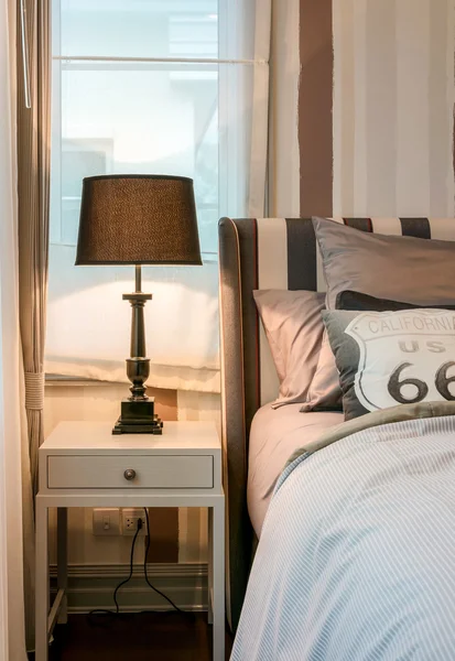 Accogliente camera da letto interna con cuscini marrone scuro e lampada da lettura sul comodino — Foto Stock