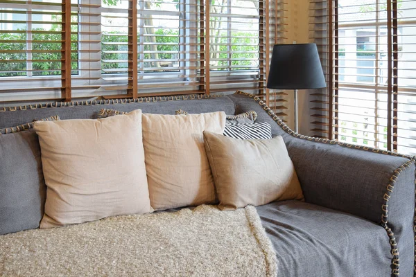 Salón interior con almohadas en sofá y mesa de madera decorativa con lámpara — Foto de Stock