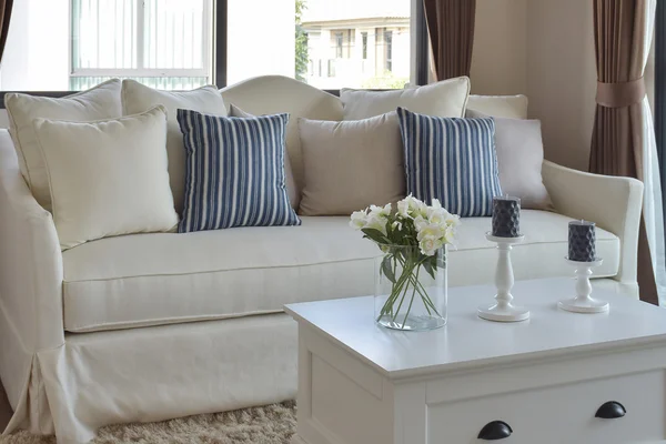 Flor decorativa en jarrón de cristal con almohadas de rayas azules en un sofá informal en la sala de estar — Foto de Stock