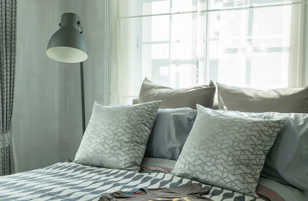 Стильный дизайн интерьера спальни с узорчатыми подушками на кровати и декоративной настольной лампой . — стоковое фото