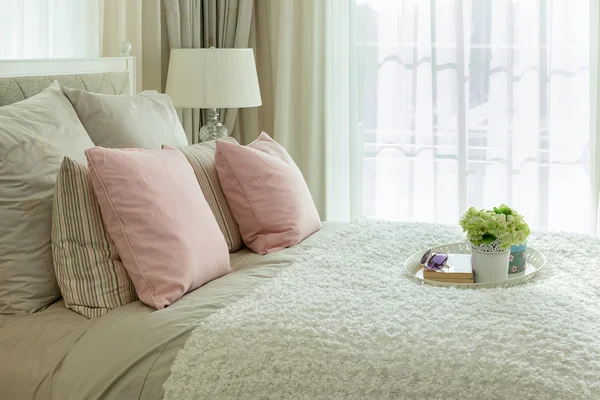 Interior do quarto de luxo com travesseiros rosa e bandeja branca de flor na cama — Fotografia de Stock