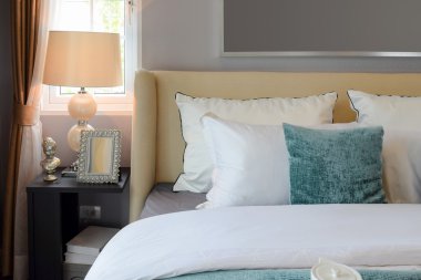 beyaz yatak ve dekoratif masa lambası beyaz ve yeşil yastık ile yatak odası iç tasarım.