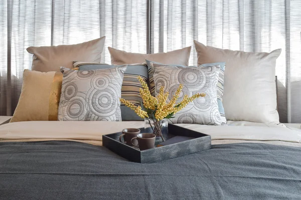 Design de interiores de quarto de luxo com almofadas listradas e conjunto de chá decorativo na cama — Fotografia de Stock