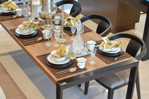 dining wooden table and comfortable chairs in modern home with elegant table setting