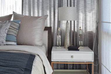 çizgili yastık yatak ve dekoratif masa lambası ile şık yatak odası iç tasarım.