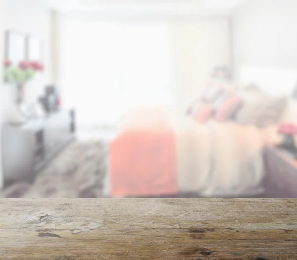 Wooden table top with blur of modern bedroom interior as background — Stock Photo, Image