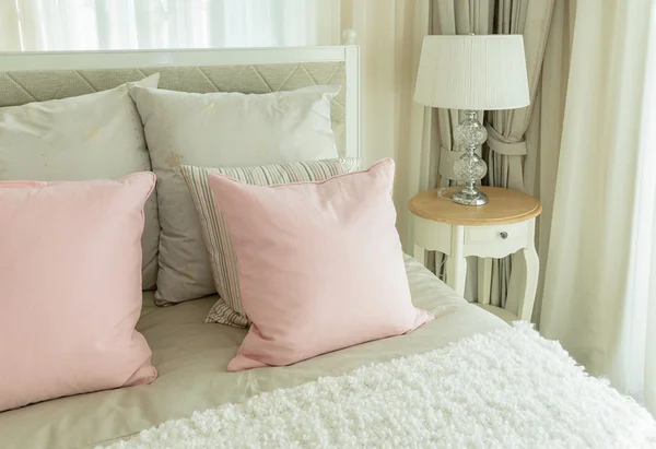 Aconchegante interior do quarto com travesseiros rosa e lâmpada de leitura na mesa de cabeceira — Fotografia de Stock