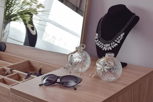 Sunglasses crystal jars and necklace on dressing table