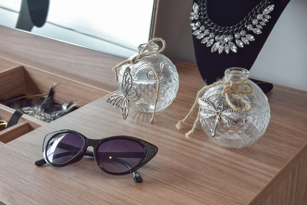Gafas de sol frascos de cristal y collar en tocador — Foto de Stock