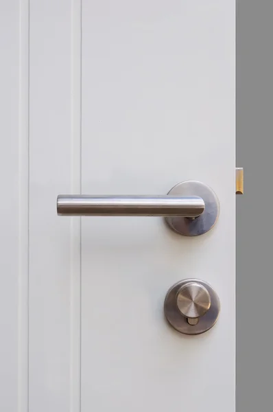 Aluminium door knob on the white door