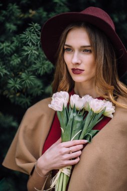 Beyaz çiçeklerle duran güzel kadın