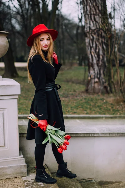 Kvinna som står på park bakgrunden med blommor — Stockfoto