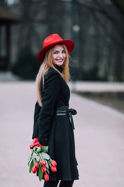 Kvinna som står på park bakgrunden med blommor — Stockfoto