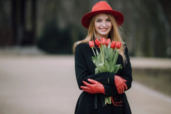 Kvinna som står på park bakgrunden med blommor — Stockfoto