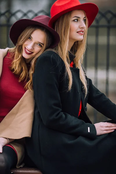 Duas meninas sentadas no banco e sorrir — Fotografia de Stock