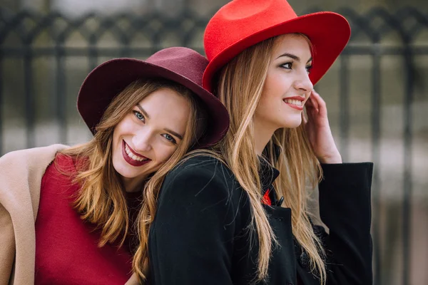 Две девушки сидят на скамейке и улыбаются — стоковое фото