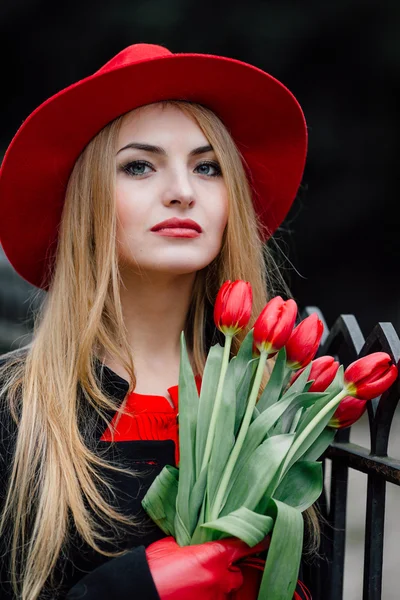 Frau steht auf dem Parkhintergrund mit Blumen — Stockfoto