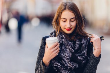 Genç kız sıcak kahve ile sokakta yürürken