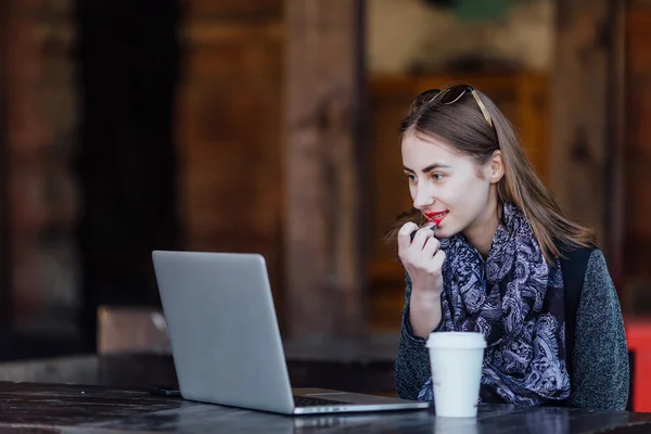 Young girl sitting behind the cafe on her laptop — Stock Photo, Image